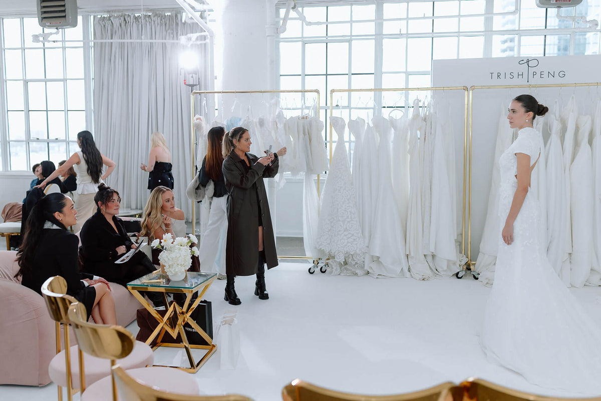 Wardrobe fitting room with people trying on wedding gowns by Trish Peng, at the bridal market