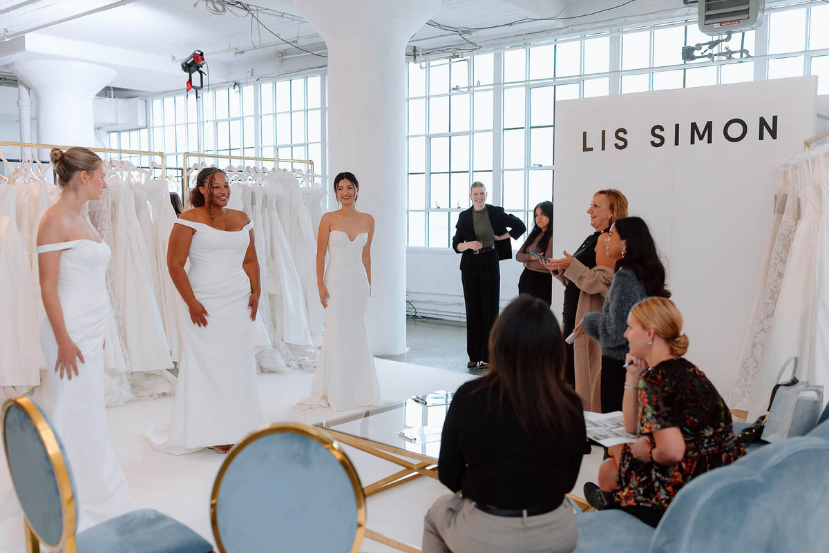 Bridal fashion show with models wearing wedding dresses in a showroom setting.
