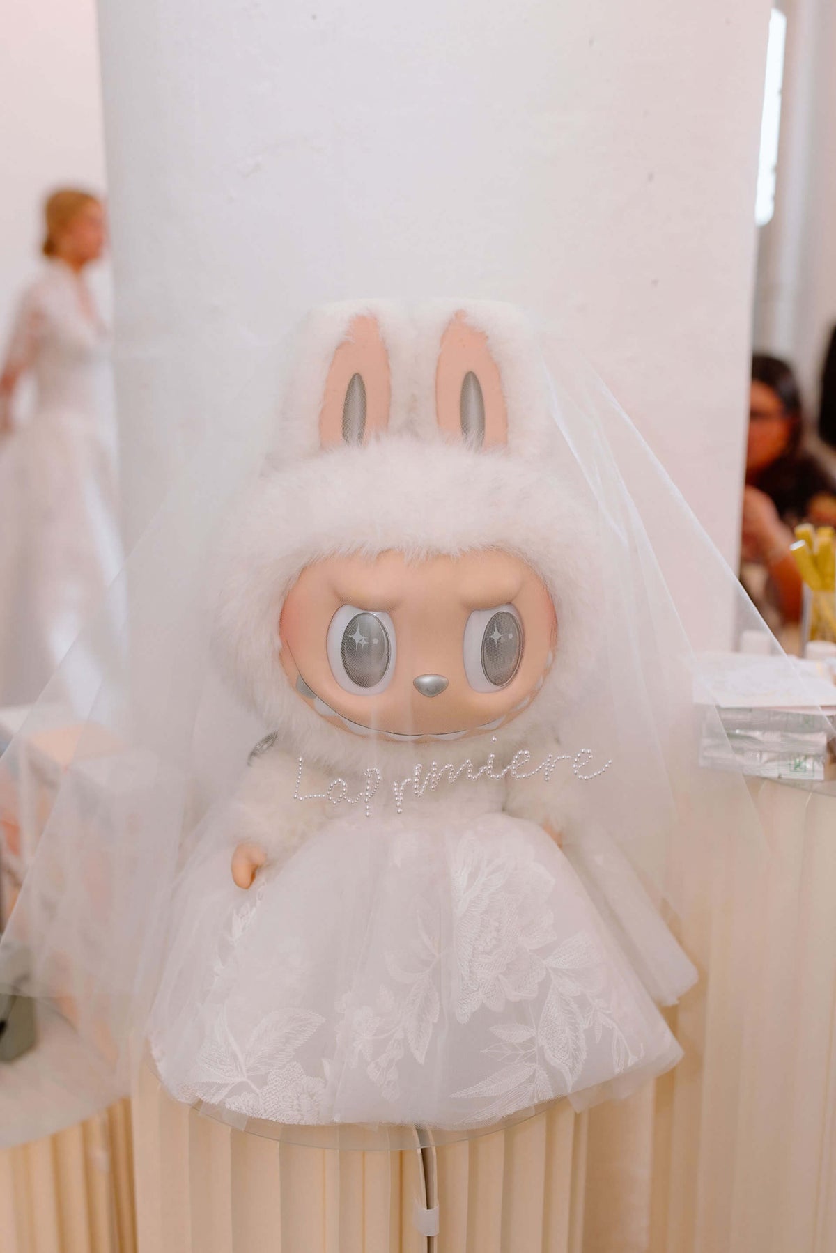 Labubu plush toy wearing a white dress against a neutral background