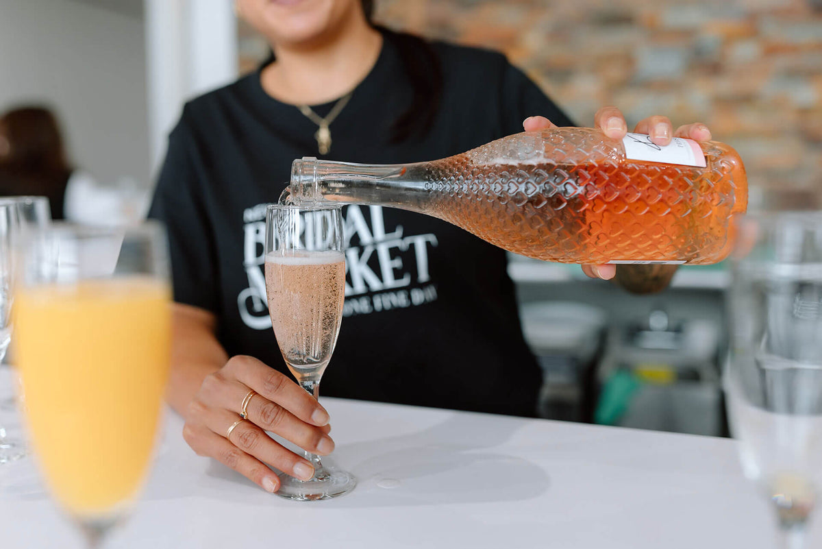 Person pouring a drink from Kylie Minogue wines into a glass.