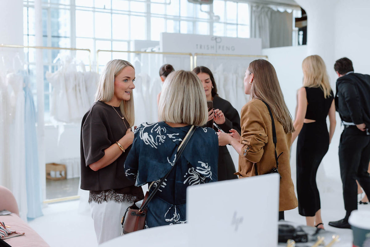 Group of women interacting in a premier bridal trade event with large windows.